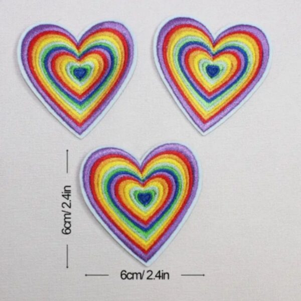 A RAINBOW LOVE HEART embroided iron on patch, perfect for personalizing clothing, bags, and accessories. Easy to apply with heat, adding a retro touch to any project.